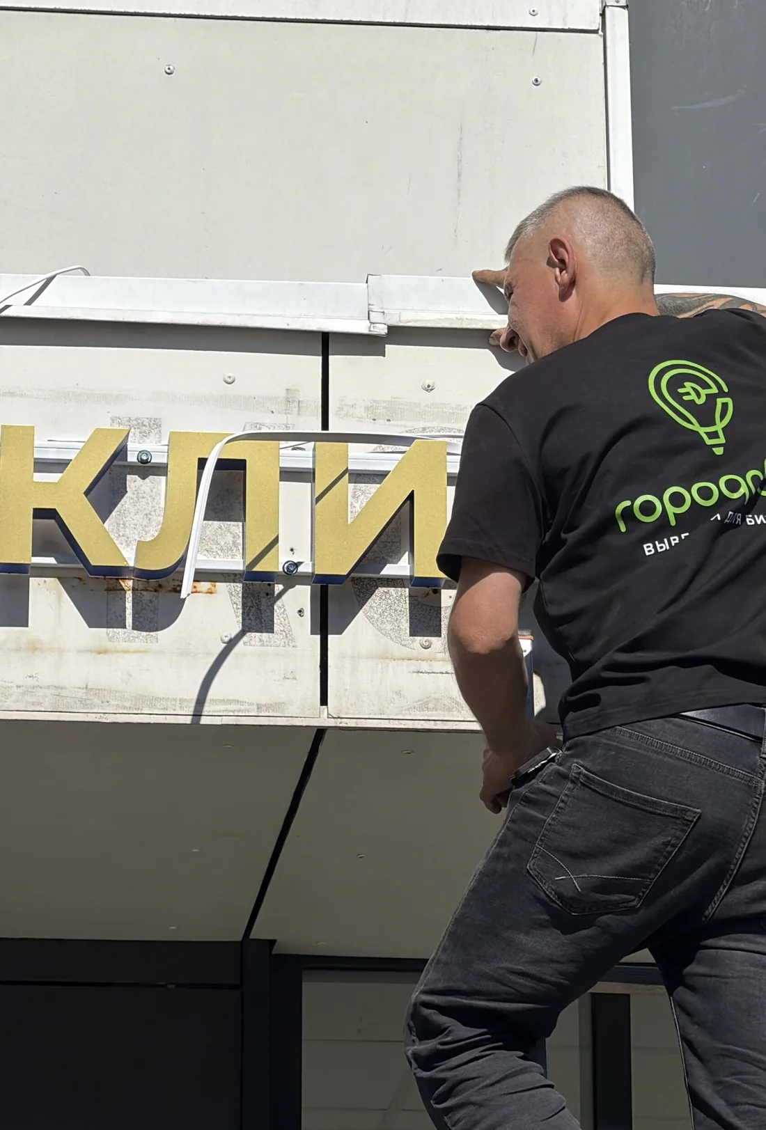 Монтажник устанавливает буквы на фасаде
