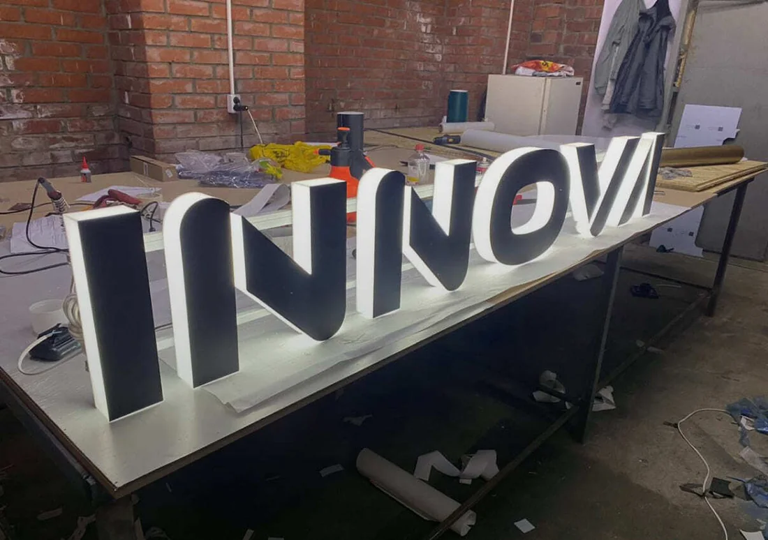 Крупные объёмные буквы INNOVA на столе в мастерской